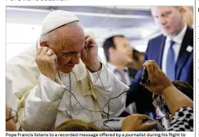  ?? ANDREW MEDICHINI / AP ?? Pope Francis listens to a recorded message offered by a journalist during his flight to Bogota, Colombia, on Wednesday. In addition to Bogota, the pope will visit Villavicen­cio, Medellin and Cartagena during his five-day apostolic trip.