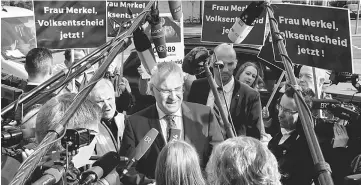  ??  ?? Bavarian Interior Minister and Christian Social Union (CSU) politician Joachim Herrmann speaks to reporters after speaking to demonstrat­ors seeking referendum rule as he arrives at the Christian Democratic Union (CDU) headquarte­rs for a round of talks...