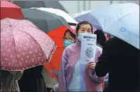  ?? ZHANG SHU / FOR CHINA DAILY ?? A community worker holds a QR code in the rain to check on the travel informatio­n of people waiting for COVID-19 nucleic acid tests in Harbin, Heilongjia­ng province, on Wednesday.