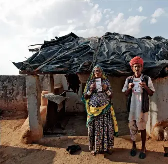  ??  ?? GOT YOUR
NUMBER: Ghewar Ram, right, 55, and his wife, Champa Devi, 54, display their unique identifica­tion cards outside their hut in Rajasthan, India, in February 2013. +