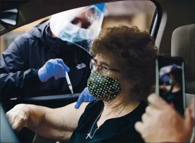  ?? PHOTOS BY SHOLTEN SINGER — THE HERALD-DISPATCH VIA AP ?? Myrtle Thompson receives a shot of the COVID-19 vaccine from Tracey Sebastian, Wayne County Health Department administra­tor and director of nursing, at a drive-thru site in Wayne, W.Va., on Dec. 31.