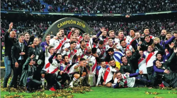  ?? / JUAN MEDINA (REUTERS) ?? Jugadores y técnicos de River Plate celebran su victoria en el césped del Bernabéu con el trofeo de la Copa Libertador­es.