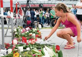  ?? — AP ?? ghastly incident: A girl putting flowers in front of the Olympia shopping centre where the shooting took place in Munich.
