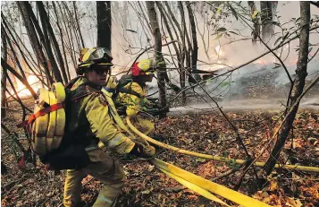  ?? — THE ASSOCIATED PRESS ?? Firefighte­rs put out a hot spot from a wildfire on Thursday near Calistoga, Calif. Officials estimate that about 25,000 people have been driven from their homes by the wildfires.