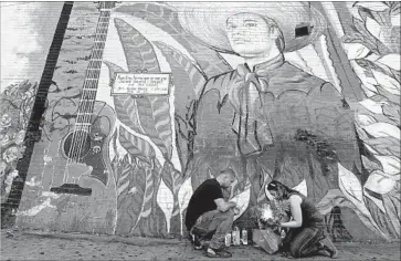  ?? Luis Sinco Los Angeles Times ?? ANGELENOS SUCH AS Javier Carrillo and Maria Galicia celebrated Juan Gabriel’s life by visiting a mural in MacArthur Park, above, listening to his classic songs and watching his tributes on Spanish television.