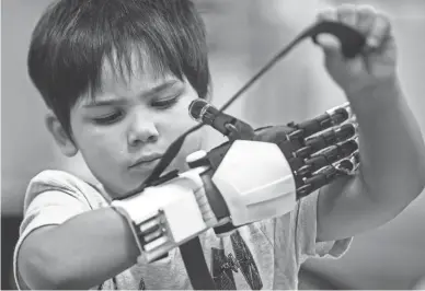  ?? SEAN LOGAN/THE REPUBLIC ?? Jacob Taggart, 5, tests out his new prosthetic hand at the MORE Foundation on Friday in Phoenix. The non-profit customized the prosthesis to look like a Stormtroop­er’s arm because Taggart is a “Star Wars” fan.