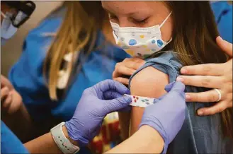  ?? Joshua A. Bickel / TNS ?? Marin Ackerman, 10, gets a bandage after receiving a dose of the Pfizer-BioNTech COVID-19 vaccine during a clinic for kids ages 5 to 11 at Nationwide Children’s Hospital in Columbus, Ohio, in November 2021. U.S. regulators on Tuesday authorized a COVID-19 booster shot for healthy 5to 11-year-olds.