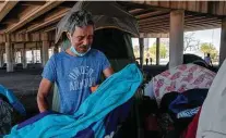  ?? Jessica Phelps / Staff photograph­er ?? Noel Garza is overcome with emotion as he picks up a blanket that belonged to his friend, who apparently died in her sleep Wednesday. They shared a tent under I-37.