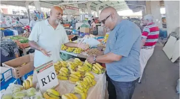  ?? | Supplied ?? RAKESH Singh helps Montford resident, Anil Chattergoo­n, select bananas.