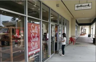  ?? JOHN RAOUX — THE ASSOCIATED PRESS ?? A sale sign at a Hallmark store Tuesday this week in Orlando, Fla. A surge in virus cases has kept people away from stores and restaurant­s during the holiday shopping season.