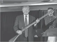  ?? RICHARD ELLIS, GETTY IMAGES ?? Then- candidate Donald Trump holds up a replica flintlock rifle given to him at The Citadel in South Carolina in February 2015.