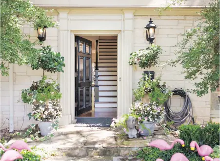  ?? MELANIE JOHNSON PHOTOGRAPH­Y/ ABBE FENIMORE VIA AP ?? Potted flowering plants creates a perfect balance with the architectu­ral moulding and a dramatic black front door at this entryway designed by Abbe Fenimore of Studio Ten 25.