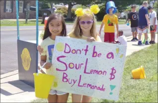  ??  ?? Rhylie Hernandez, left, and Alaina Bagbuy stand with a sign for the Alex’s Lemonade Stand at Oak Ridge Elementary School.