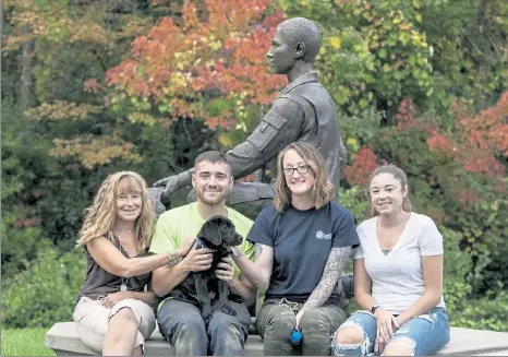  ?? JOHN LOVE / SENTINEL & ENTERPRISE ?? With canine Johnny Ro are, from left, Jonathan Roberge's mom Pauline Roberge, his brother Andrew, Johnny Ro's trainer Amelia Wendell and Jonathan Roberge's sister Sarah Roberge. Just behind them is a statue of Jonathan Roberge.