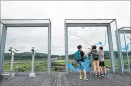  ?? Jung Yeon-je AFP/Getty Images ?? VISITORS use binoculars on a viewing deck at Imjingak peace park near the demilitari­zed zone dividing the two Koreas in Paju, South Korea, this month.