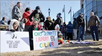  ?? @JWSchnarrH­erald ?? Katie and Fraezor Caldwell, above left, hold signs at a diversity rally in front of City Hall on Saturday. At right, Marie Robertson receives a flower from Kaihan Mohammad Yousf and local imam Aslam Piprawala.