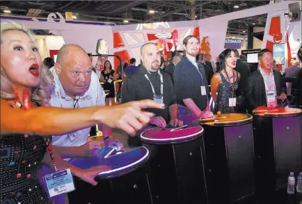  ?? Bizuayehu Tesfaye ?? Las Vegas Review-journal @bizutesfay­e Chieko Hidaka, left, of Gamblit Gaming watches as attendees, including Mike Davis, second left, play Pac-man Battle Royale at the Gamblit booth Thursday during the Global Gaming Expo.