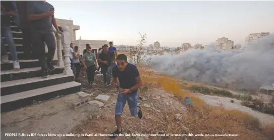  ?? (Mussa Qawasma/Reuters) ?? PEOPLE RUN as IDF forces blow up a building in Wadi al-Hummus in the Sur Bahir neighborho­od of Jerusalem this week.