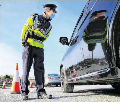  ?? PHOTO: GERRY MOONEY ?? On the move: A garda talks to a driver at a checkpoint on the N7 near Naas yesterday.