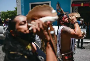  ??  ?? Activists blow on conch shells Saturday during a march demanding statues and street names commemorat­ing symbols of colonial oppression be removed in San Juan, Puerto Rico.