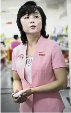  ?? — AP ?? Going upmarket: A woman (left) looking at a display of imported cosmetics and perfume sold on the second level of the Potonggang department store while store manager Song (above) stands in the snacks aisle while being interviewe­d.