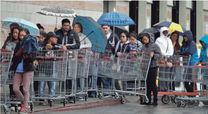  ?? BEN MARGOT/AP ?? Costco customers wait in the rain to enter the store on Saturday, in San Leandro, Calif. Efforts to stop the spread of the coronaviru­s in California are affecting virtually every facet of life in the Golden State in ways big and small.