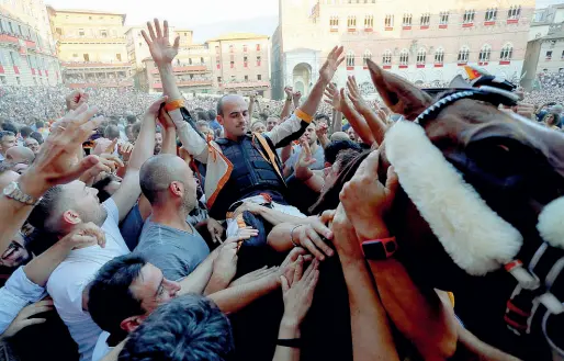  ??  ?? Il giubilo dei contradaio­li della Lupa dopo la vittoria del fantino Gingillo sul cavallo Porto Alabe, sotto il Drappellon­e di Charles Szymkowicz portato in trionfo dopo la Carriera (foto: Fabio Muzzi)