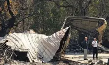  ??  ?? RON LOCATELLI, right, and an insurance adjuster talk at the site of the volunteer firefighte­r’s former home on Fisher Lake Drive.