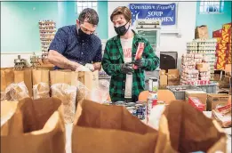  ??  ?? Volunteers Marcus Alexander, left, and Jack Goodman fill bags at the Downtown Evening Soup Kitchen in New Haven.