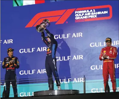  ?? (AP/Darko Bandic) ?? Red Bull driver Max Verstappen of the Netherland­s (center) holds his trophy Saturday as he stands on the podium with second place finisher Sergio Perez of Mexico (left) and third place finisher Carlos Sainz of Spain during the Formula One Bahrain Grand Prix at the Bahrain Internatio­nal Circuit in Sakhir, Bahrain.