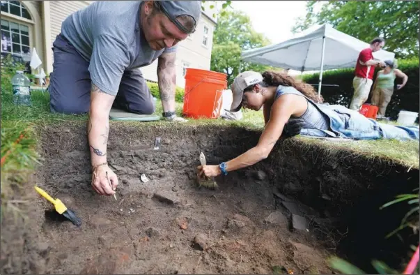  ?? (File Photo/AP/Steven Senne) ?? University of Massachuse­tts Boston graduate students Nicholas Densley (left), of Missoula, Mont., and Kiara Montes, of Boston, use brushes while searching for artifacts at an excavation site on June 9 on Cole’s Hill in Plymouth, Mass.