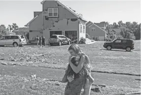  ?? JOE LAMBERTI/CAMDEN COURIER-POST VIA AP ?? Kenley Thomas is hugged by her neighbor Natalie Bonnenberg on Thursday after homes in Mullica Hill, N.J., were damaged by a tornado.