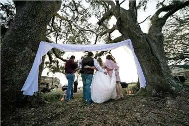  ?? Associated Press ?? ■ Emily and Taylor Pascale pose for photos after getting married Dec. 4 outside the home of Taylor’s parents in Grand Lake, La., which was heavily damaged from hurricanes Laura and Delta.