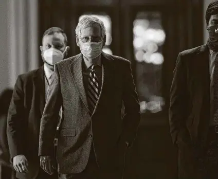  ?? Ting Shen / Bloomberg ?? Senate Majority Leader Mitch Mcconnell, a Republican from Kentucky, center, wears a protective mask while walking through the Capitol. He blocked an attempt by Democrats to force quick action increasing direct stimulus payments to $2,000.