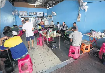  ??  ?? A TASTE OF HOME: A small restaurant in the Myanmar community in Phuket. Many migrants arrived in Phuket at a young age. Some entered Thailand illegally and gained work permits later.