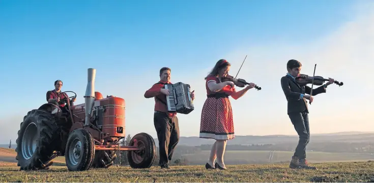  ??  ?? BEAT SURRENDER: Musicians Alan Small, Gemma Donald and 10-year-old Andrew Farquharso­n join Clark Farquharso­n, at the wheel of the tractor, for music down on the farm.