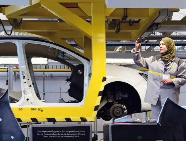  ?? © Afp/farouk Batiche ?? Une employée du groupe Renault prend une photo lors de l’inaugurati­on du site de fabricatio­n d’oued Tlélat, près d’oran, en novembre 2014.