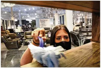  ?? BILL LACKEY / STAFF ?? Morris Home Furniture sales profession­al Kayla Gregg dusts off some of the items in the showroom between customers Friday at Morris’ Beavercree­k store.