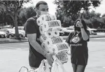  ??  ?? Volunteer Raj Thakur unloads a stack of toilet paper and other goods.