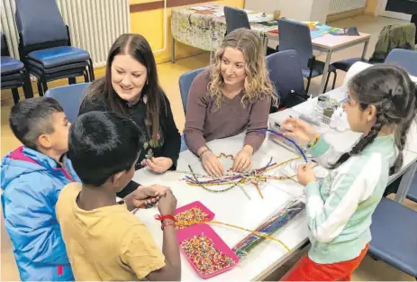  ?? FOTO: MÖCKLIN ?? Mit glitzernde­n Pfeifenput­zern und Perlen basteln Flüchtling­skinder in der Kinder- und Jugendbetr­euung der LEA bunte Weinachtss­terne. Amelie Matzik und Anne Sandmaier (von links) sind für sie da.