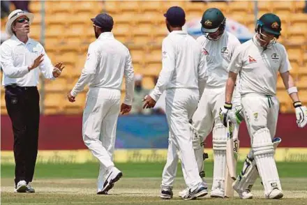  ?? REUTERS PIC ?? India’s Virat Kohli (second from left) speaks to the umpire as Australia’s Steven Smith (right) walks off the ground during their second Test in Bangalore on Tuesday.