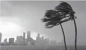  ?? JOE RAEDLE/GETTY IMAGES ?? The outer bands of the hurricane reach the Miami skyline. Though Miami is no longer in the direct path of the storm, it did not escape its force.