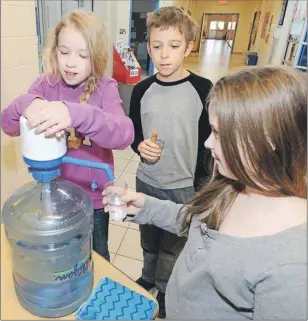  ?? HEATHER TAWEEL/THE GUARDIAN ?? Kate Lowe pumps water for Mary Soucy and Andrew Hrickyw at Ecole St. Augustin. The school goes through over 200 water bottles every three weeks from five water stations throughout the school.
