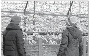  ?? AP/LEE JIN-MAN ?? Visitors stand Tuesday near the fence decorated with South Korean national flags at the Imjingak Pavilion in Paju, South Korea, on the day of a meeting between North and South Korean negotiator­s on the Winter Olympics and other issues.