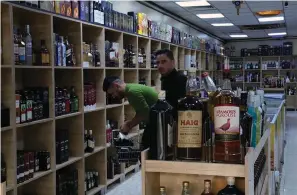  ?? The Associated Press ?? ■ People buy alcohol in a liquor store Thursday in Baghdad, Iraq. Only a few months into its term, Iraq’s government is suddenly enforcing a long-dormant law banning alcohol imports and arresting people over social media content deemed morally offensive. The crackdown has raised alarm among religious minorities and rights activists.