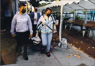  ?? JOSE CARLOS FAJARDO — STAFF PHOTOGRAPH­ER ?? From left, Shahil Khan, of Vacaville, Cristian Colin, of Suisun City, and Carlyon O’Neill, of Suisun City, carry their takeout order back to their car after picking up food from Broderick Roadhouse in Walnut Creek on Monday. Outside eating areas at restaurant­s have been closed due to shelter-in-place orders that went into effect in many Bay Area counties on Monday.