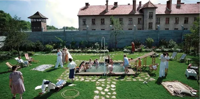  ?? ?? Los niños en el
agua y los adultos en las
tumbonas disfrutan del jardín de los
Hoss con Auschwitz de fondo en ‘La zona de interés’.