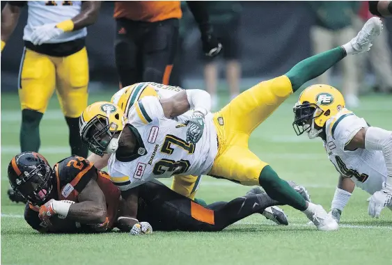  ?? — THE CANADIAN PRESS ?? Lions running back Jeremiah Johnson gets tackled by Edmonton defensive back Kenny Ladler during first half CFL action Saturday in Vancouver. The Lions won 32-25.