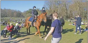  ?? (AP/Sylvain Plazy) ?? Police patrol as people enjoy unseasonab­ly warm weather at the Bois de la Cambre park in Brussels.