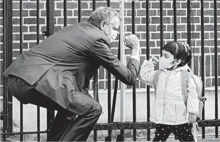  ?? TODD HEISLER/THE NEW YORK TIMES ?? Mayor Bill de Blasio greets a student this week at Mosaic Pre-K Center in the Queens borough of New York City by bumping elbows.